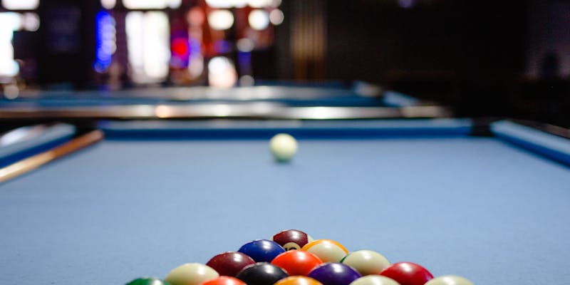 Pool table with scattered balls under dramatic blue lighting